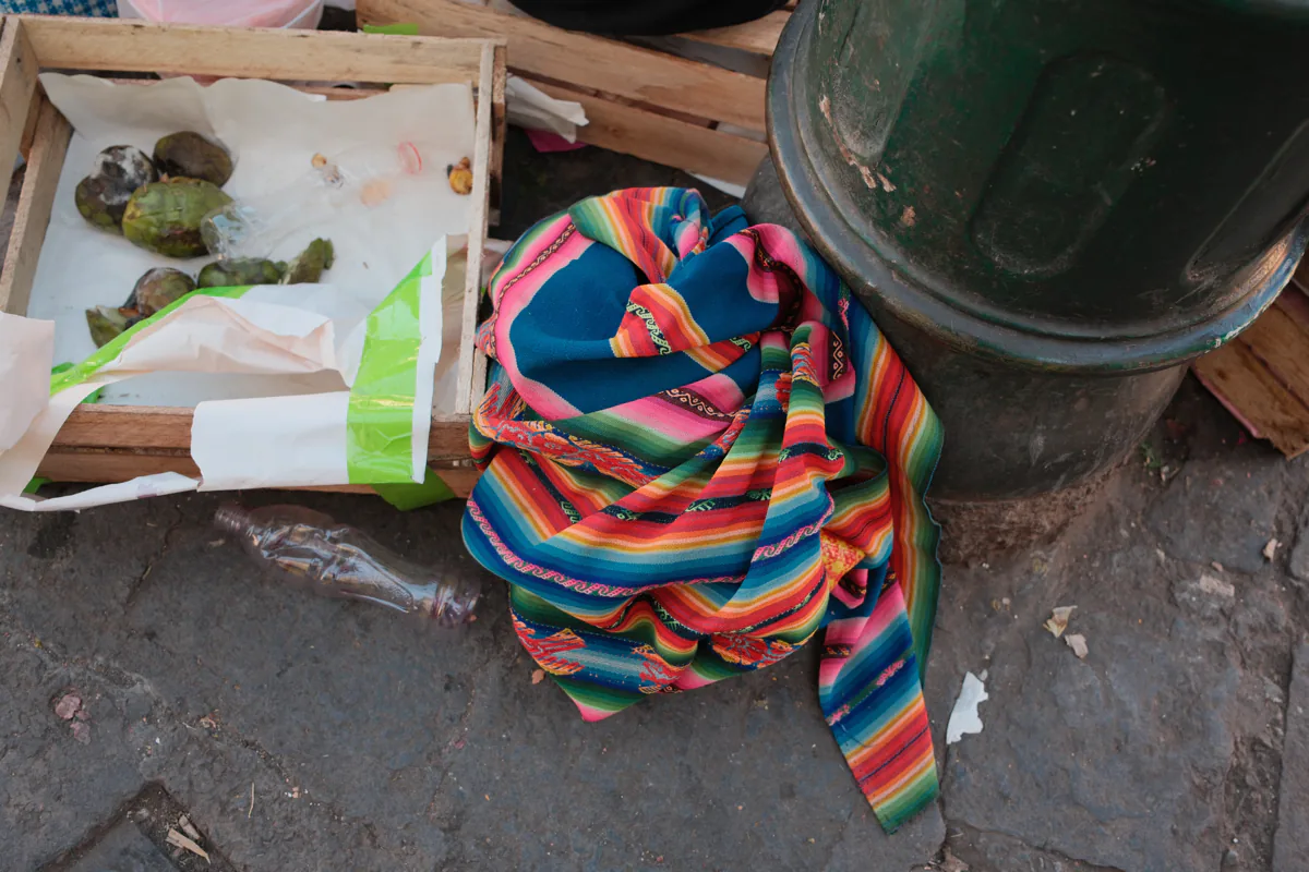 Ein Mann trägt an einer Strassenkreuzung in Cusco ein gestreiftes Textil.